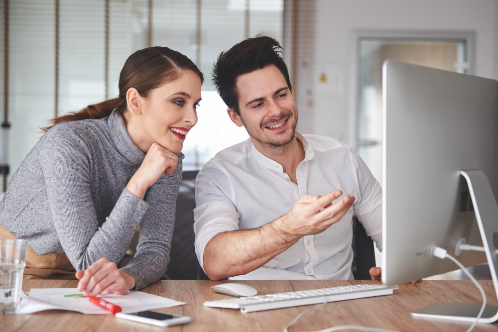 un couple souriant devant un ordinateur